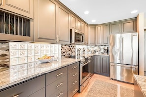 A modern kitchen with stainless steel appliances, a tiled backsplash, and a granite countertop. - 3 BR Waterfront Retreat with Private Beach Access and Stunning Ocean Views (Freeland)