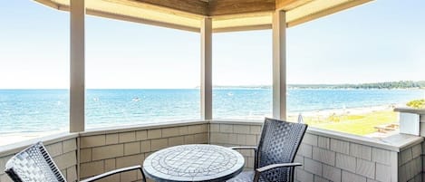 Un'area esterna coperta con tavolo e sedie, con vista su un corpo d'acqua.