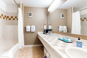 A bathroom with a bathtub, a sink, a mirror, and a shower curtain.