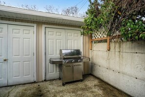 Eine Garage mit einem Edelstahl-Barbecue und einer weißen Tür.