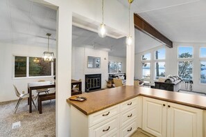 Een keuken met witte kastjes, een houten aanrechtblad en hanglampen.
