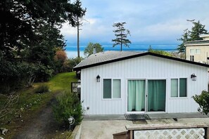 Ein eingeschossiges Haus mit einer Veranda und Blick auf den Ozean, inklusive sichtbarer Tür.