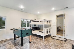 A room with a bunk bed, a foosball table, and a window. - Spacious 3 Bedroom Greenbank Home with Beach Access and Game Room (Greenbank)