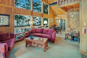 Un intérieur de cabine spacieux, avec un revêtement en bois, de grandes fenêtres, un canapé rouge et un coin repas.