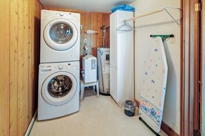 Une petite buanderie équipée d’une machine à laver et d’un sèche-linge superposés, d’un petit radiateur et d’un étendoir.