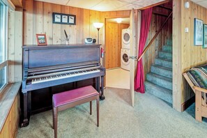 Een kamer met een piano, een wasmachine en een trap.