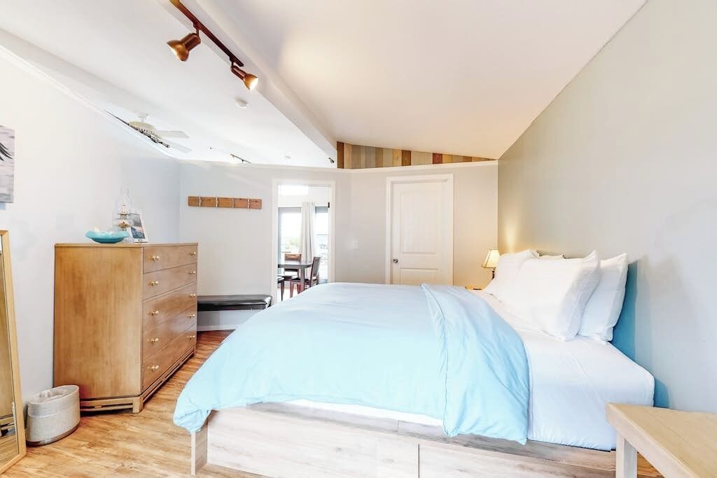 Een slaapkamer met een bed, een houten dressoir en een bureau.