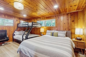 Ein Zimmer einer Holzjagdhaus mit Etagenbetten, einem Fernseher und einem Fenster.