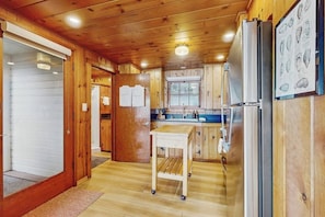 Ein Holzinterieur mit Küchenzeile, einschließlich Schränken, einem Kühlschrank und einem Esstisch.