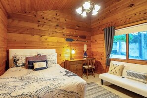 A wooden cabin room with a bed, desk, chair, and a window with curtains. - Family friendly, Two-Story Retreat with Deck, grill and Ocean Views (Coupeville)
