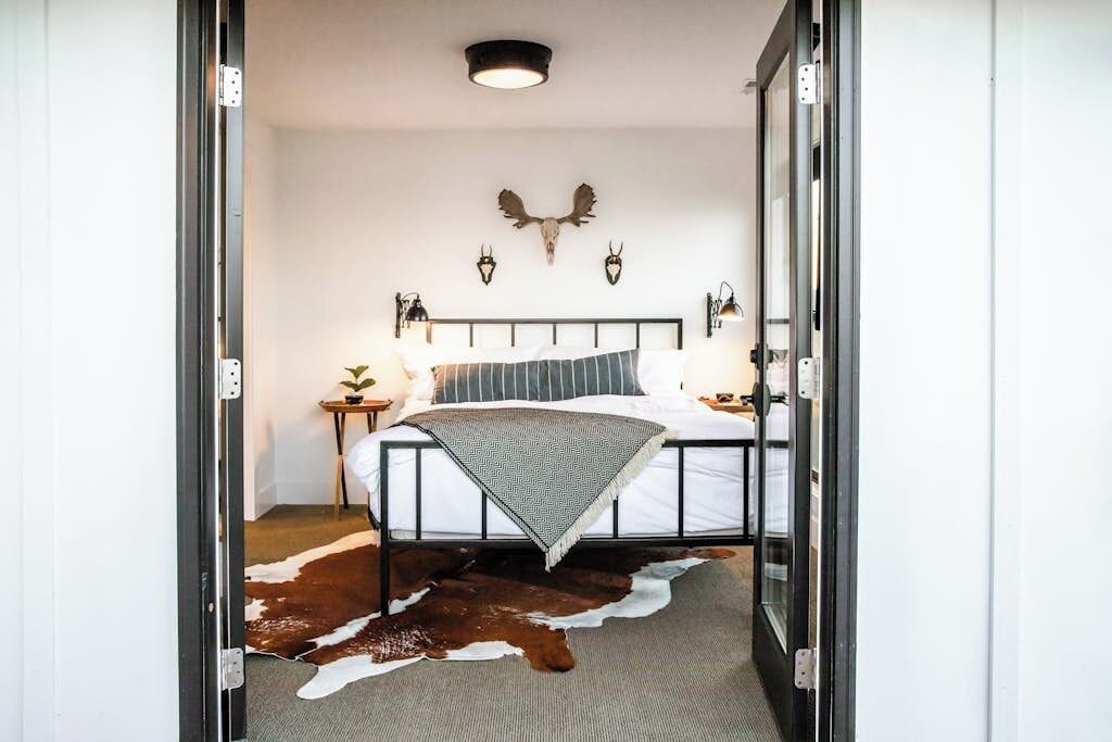 Un dormitorio con una cama, un tapiz de cuero de vaca y cuernos de animales colgados en la pared.