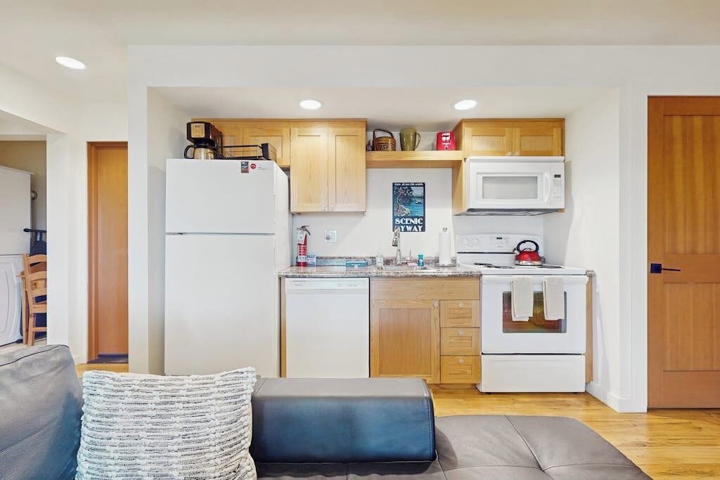 Una cocina compacta con electrodomésticos blancos, armarios de madera y un microondas.