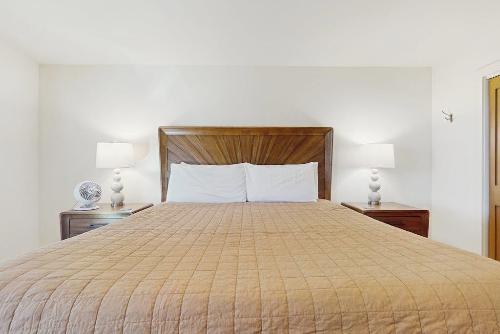 Ein Hotelzimmer mit einem großen Bett, zwei Nachttischen mit Lampen und einem Holzkopfteil.