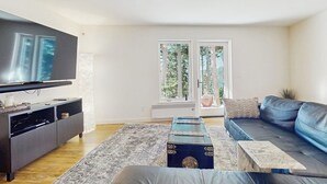 A modern living room with a flat-screen TV, a dark sofa, a coffee table, and a patterned rug.