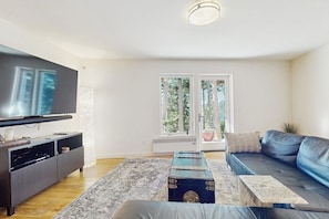A modern living room with a flat-screen TV, a dark sofa, a coffee table, and a patterned rug.