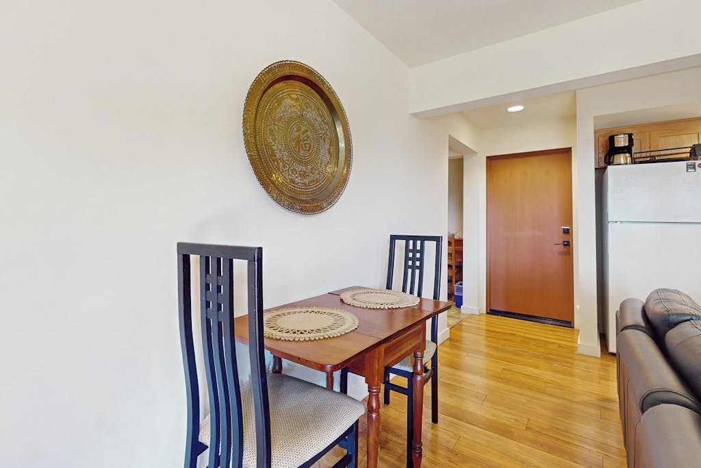 A dining area with a wooden table, two chairs, and a decorative plate on the wall.
