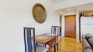 A dining area with a wooden table, two chairs, and a decorative plate on the wall.