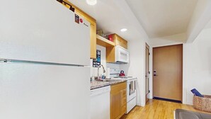 A compact kitchen with a refrigerator, microwave, and stove.