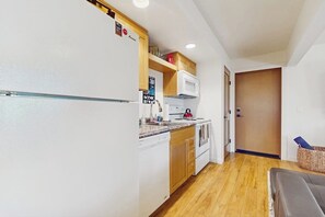 A compact kitchen with a refrigerator, microwave, and stove.