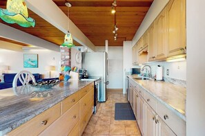 A kitchen with wooden cabinets, a marble countertop, and a refrigerator.