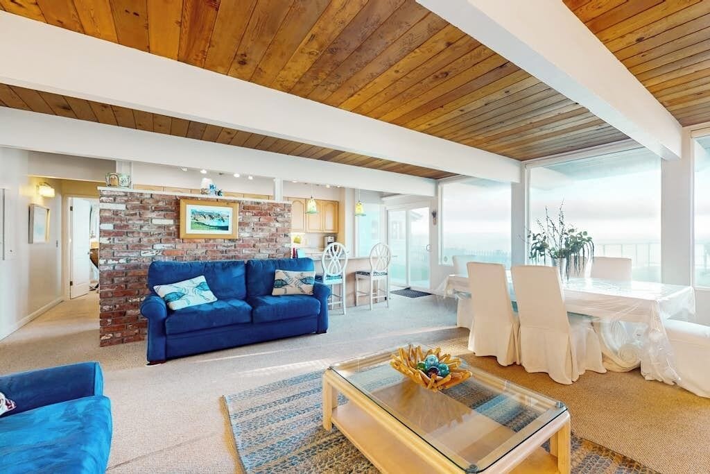 Un amplio salón con un sofá azul, una mesa de centro y una pared decorativa de ladrillo.