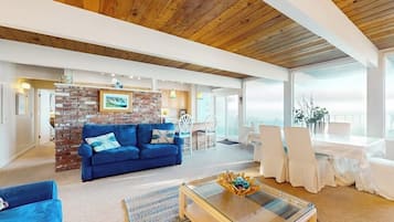 A spacious living area with a blue sofa, a coffee table, and a brick accent wall.