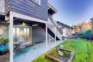 A residential property with a covered porch, a staircase, a small garden, and a patio area.