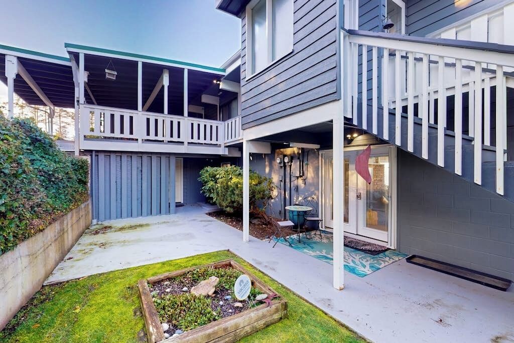 A two-story house with a covered patio, a small garden, and a staircase leading to the upper level.