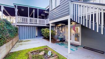 A two-story house with a covered patio, a small garden, and a staircase leading to the upper level.