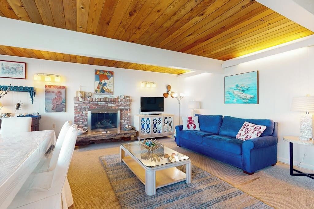 Ein Wohnzimmer mit Kamin, einem blauen Sofa und einem Fernseher.