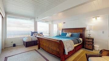 A bedroom with a large bed, a bedside table, a window with a view, and a ceiling with wooden beams.