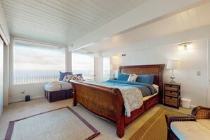 Une chambre à coucher avec un grand lit, une table de chevet, une fenêtre donnant sur un beau paysage et un plafond avec des poutres en bois.