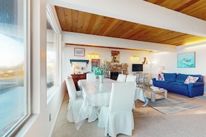 A dining area with a round table and white chairs, a blue sofa, and a fireplace.