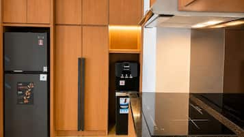 A kitchen with wooden cabinets, a black refrigerator, a coffee machine, and a black induction cooktop.