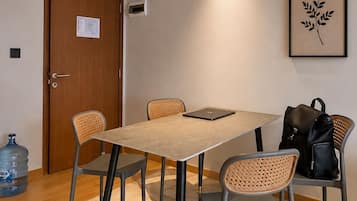 A conference room with a rectangular table, four chairs, a laptop, a water dispenser, and a framed plant on the wall.