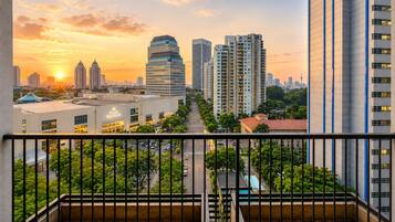 A cityscape view from a balcony with high-rise buildings, a clear sky, and a sunset.
