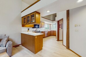 Eine moderne Küche mit Holzschränken, einer zentralen Kochinsel und einer eingebauten Mikrowelle.