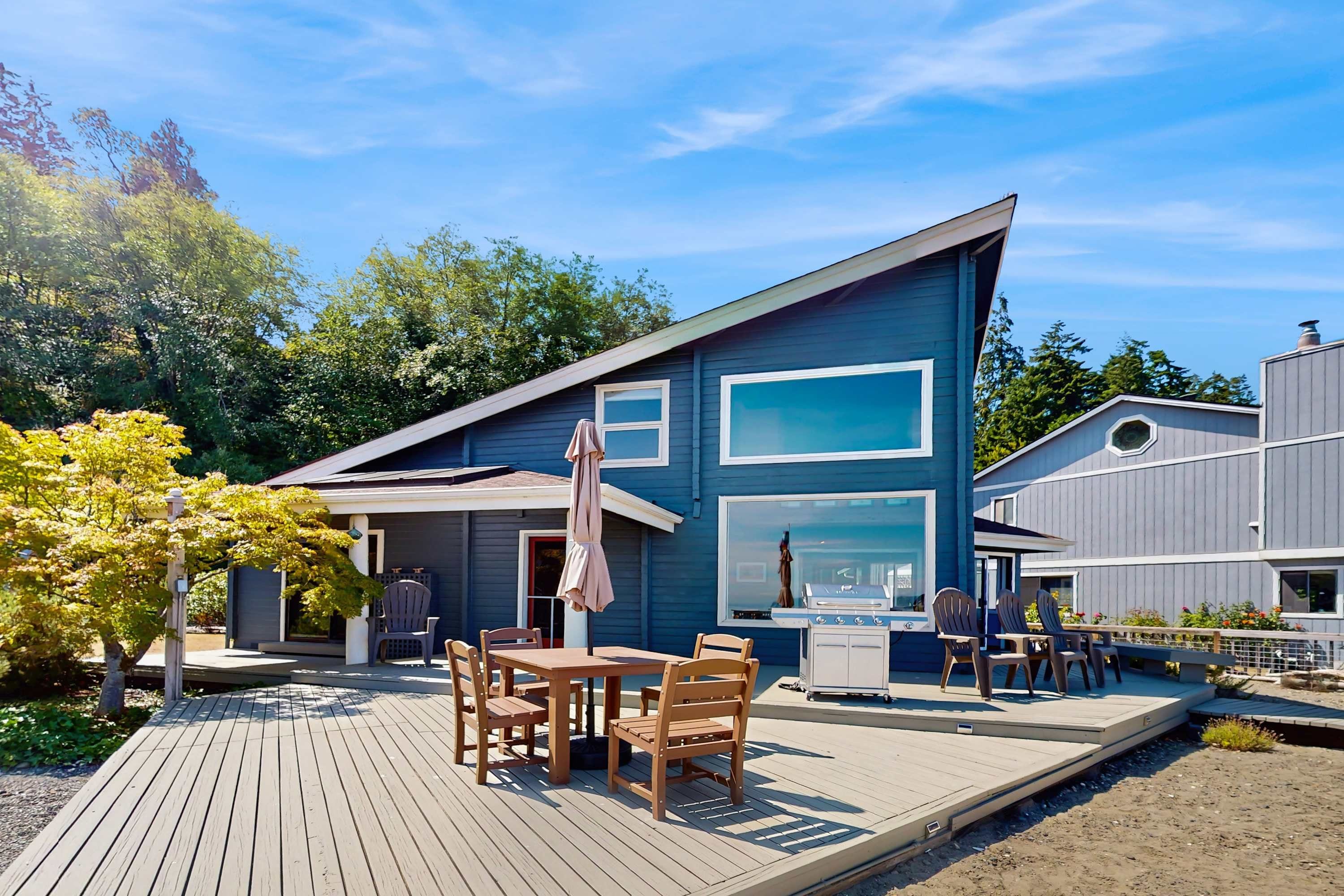Une maison moderne dotée d’une terrasse, d’un espace salon extérieur et d’un coin barbecue.