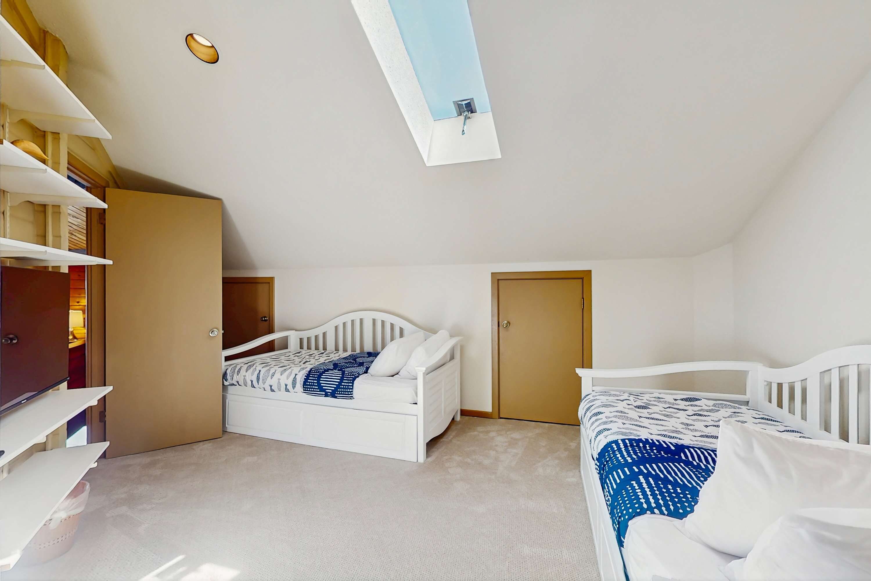 A bedroom with two beds, a wardrobe, and a skylight.
