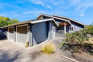 Ein zweistöckiges Haus mit Garage, überdachter Veranda und kleinem Garten.