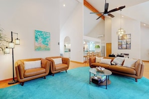 A spacious living area with two leather sofas, a coffee table, and a ceiling fan. - Pet Friendly Waterfront House in Oak Harbor with Sauna and Tennis Court (Oak Harbor)