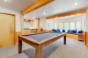 A pool table in a room with a wooden ceiling, a seating area with blue cushions, and a window with blinds. - Pet Friendly Waterfront House in Oak Harbor with Sauna and Tennis Court (Oak Harbor)
