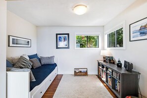 Ein Zimmer mit einem Bett, einem Bücherregal und einem Fenster mit Blick auf Grünflächen.