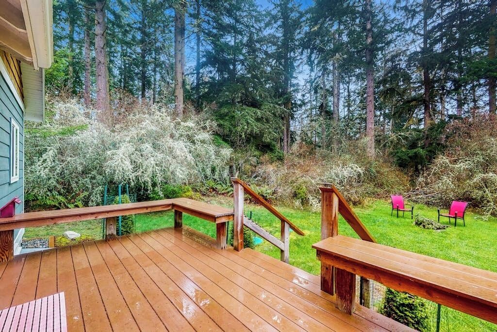 Une terrasse en bois avec un escalier menant à une zone herbeuse où se trouvent des chaises.