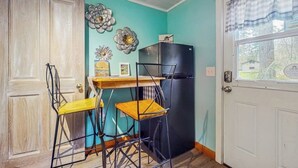 Una cocina con puerta de madera, un refrigerador negro y una ventana con cortina a cuadros.
