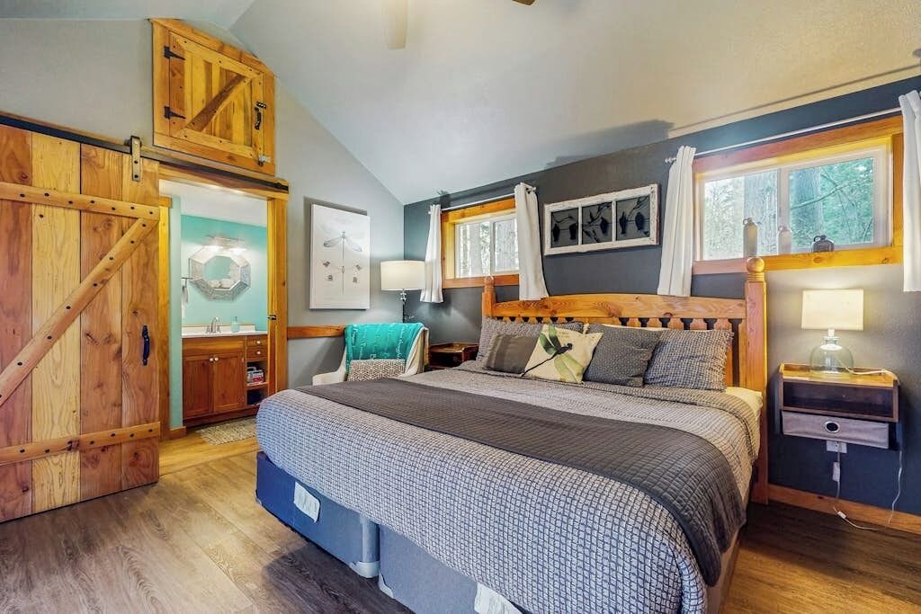Een slaapkamer met een groot bed, een houten hoofdbord, een nachtkastje, een dressoir en een garderobe.