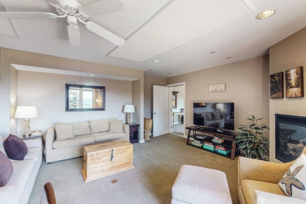 A living room with a sofa, a television, a fireplace, and a ceiling fan.