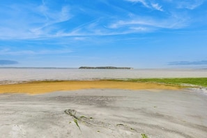 Ein Strand mit blauem Himmel, einer fernen Insel und sandigem Vordergrund.