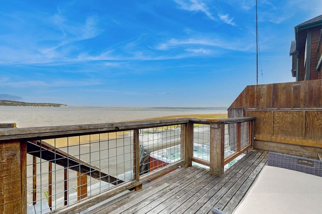 A wooden deck with a metal railing overlooking a beach.