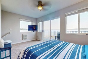 Quarto com uma cama grande, televisão na parede e varanda com vista.